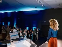 Who We Are: woman speaking to a an audience.